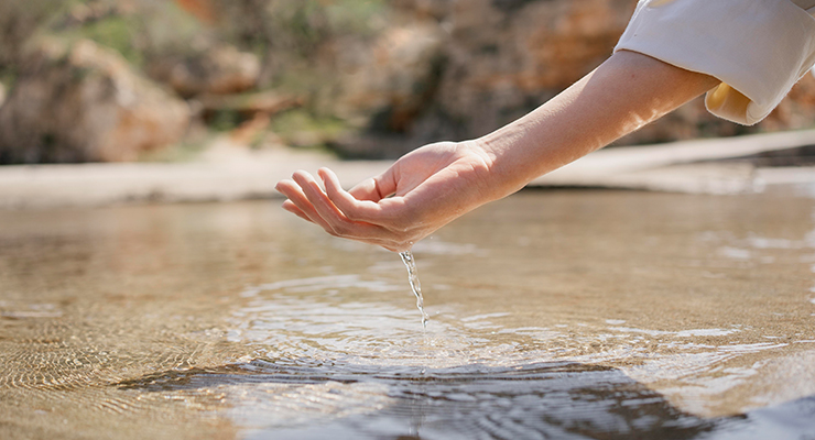 Hand greift in Wasser mit PFAS in der Umwelt